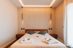 Une chambre d’hôtel avec un lit bien fait, une tête de lit en bois et un luminaire au plafond.