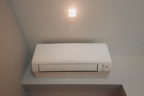 Una impresora blanca sobre una superficie blanca, con una luz de techo arriba.