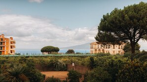 A coastal building complex with multiple structures, a large tree, and a view of the sea. - Sama Apartments – Elegance, Comfort and Sea View in the Heart of Sorrento (Sorrento)