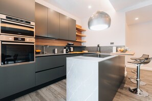 Une cuisine moderne dotée d’appareils électroménagers intégrés, d’un îlot central et de tabourets de bar.