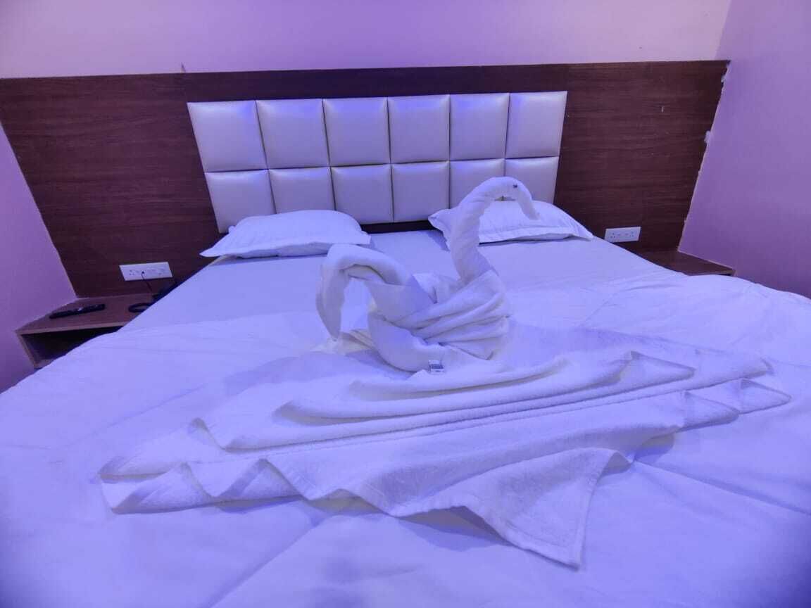 A hotel room with a bed featuring a swan-shaped towel arrangement.