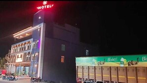 A hotel with a prominent 'HOTEL' sign at the top, a balcony on the upper floor, and a signboard with 'Bişleri' visible.