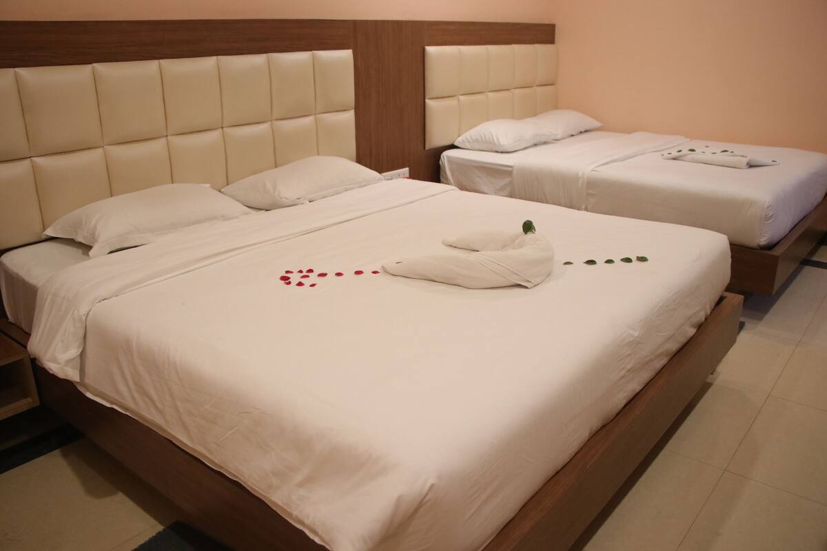 Ett hotellrum med två sängar, var och en med en sänggavel och vita sängkläder.