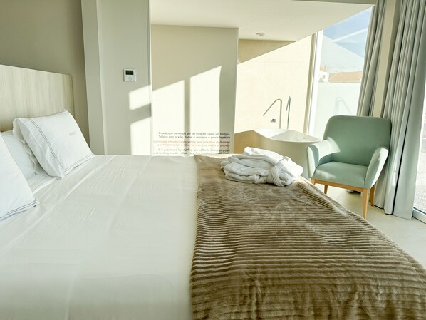 A hotel room with a bed, a chair, and a view of the outside. - Otantus Hotel (Muros)