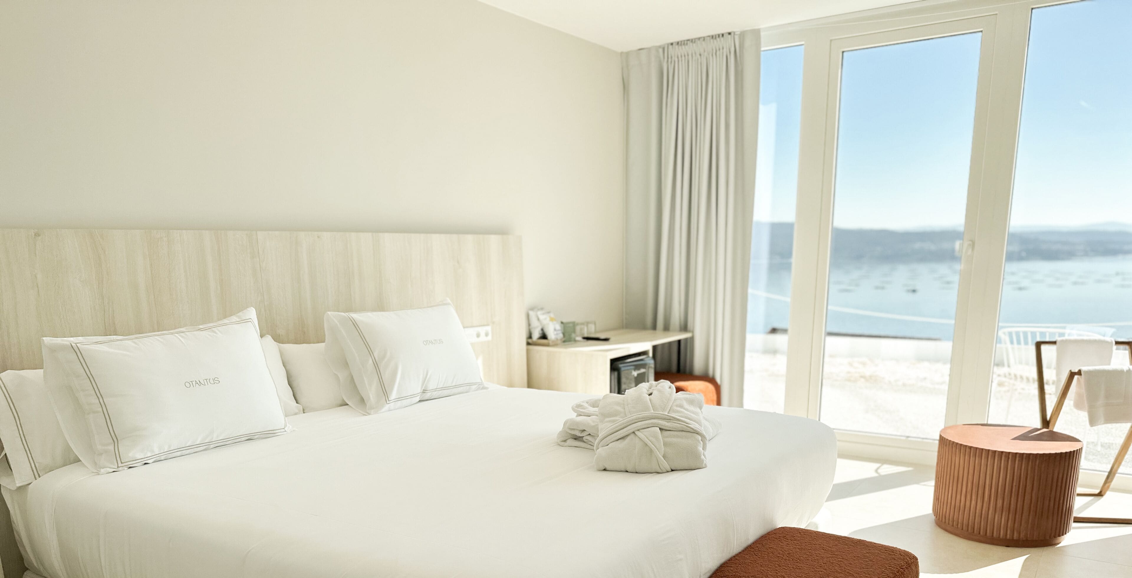 Une chambre d’hôtel avec un grand lit, une table de chevet, une vue sur la plage et une petite table ronde.