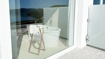 Un baño moderno con bañera, ducha y un balcón con cerramiento de vidrio que ofrece vistas panorámicas.