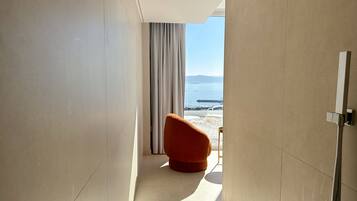 A modern bathroom with a shower, a view of the beach, and a red chair.
