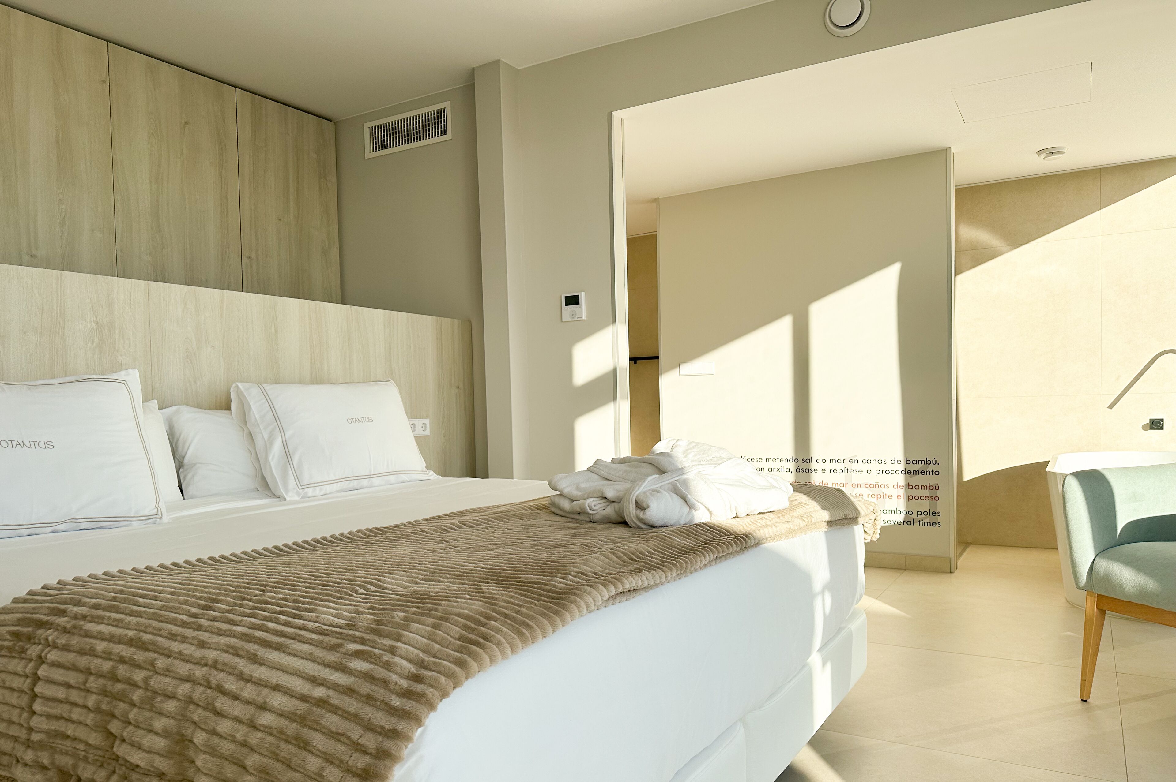 Habitación de hotel moderna con una cama grande, cabecera de madera y vistas al exterior.