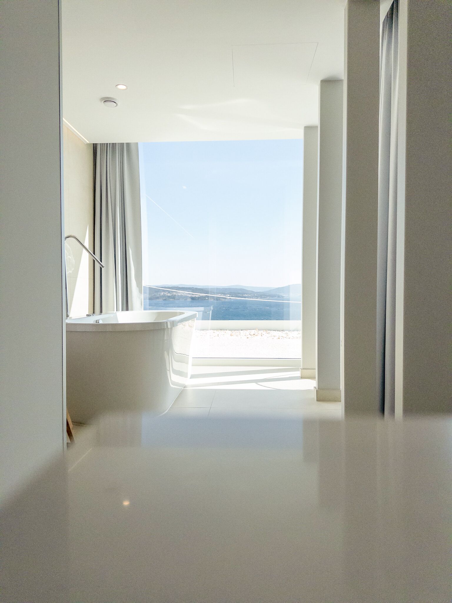 Une salle de bain moderne dotée d’une grande baignoire, d’une douche et offrant une vue sur la plage.