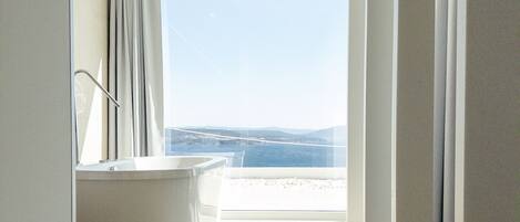 Une salle de bain moderne dotée d’une grande baignoire, d’une douche et offrant une vue sur la plage.