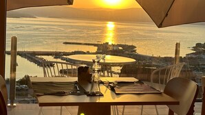 A table with chairs and a view of the sunset over the water. - Otantus Hotel (Muros)