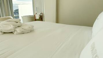 Habitación de hotel con una cama bien hecha, una ventana con cortinas y vistas al exterior.