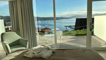 Una stanza con un'ampia porta-finestra scorrevole che dà su un balcone con vista su un lago e montagne.