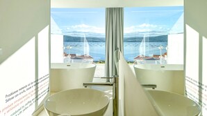 A bathroom with two large white basins and a view of a body of water with boats. - Otantus Hotel (Muros)