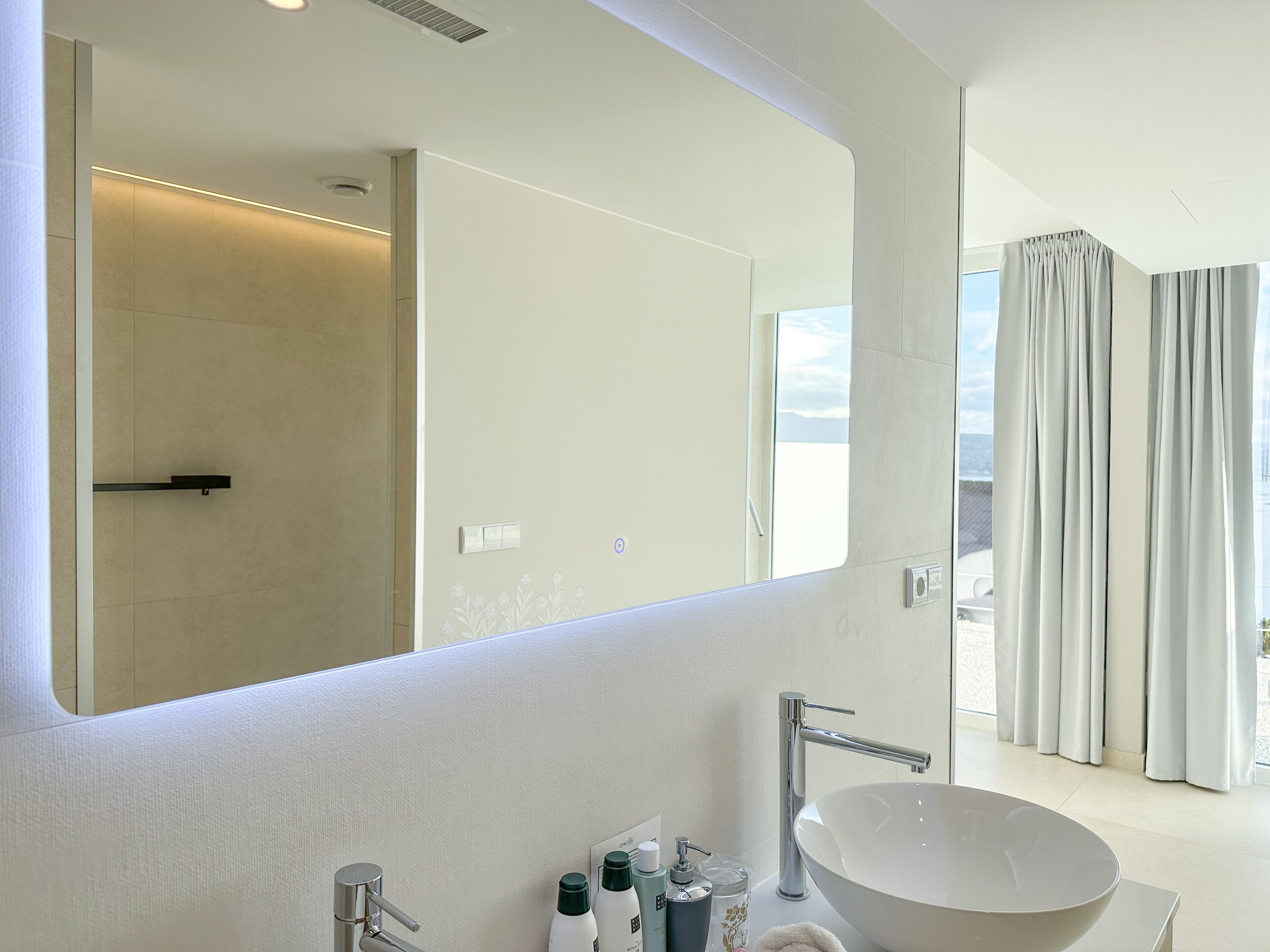 Un baño moderno con un espejo grande, un lavabo independiente y una zona de ducha.