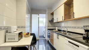 Une cuisine moderne avec des meubles blancs, un plan de travail noir et un coin repas comprenant une table et des chaises.