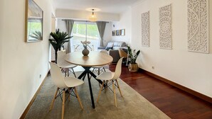 Un coin repas avec une table ronde, des chaises blanches et un lustre.