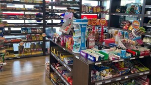 A grocery store with shelves stocked with snacks, beverages, and household items.