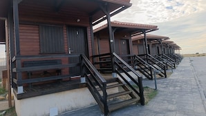 A row of wooden cabins with external staircases, each with a door marked with a number.