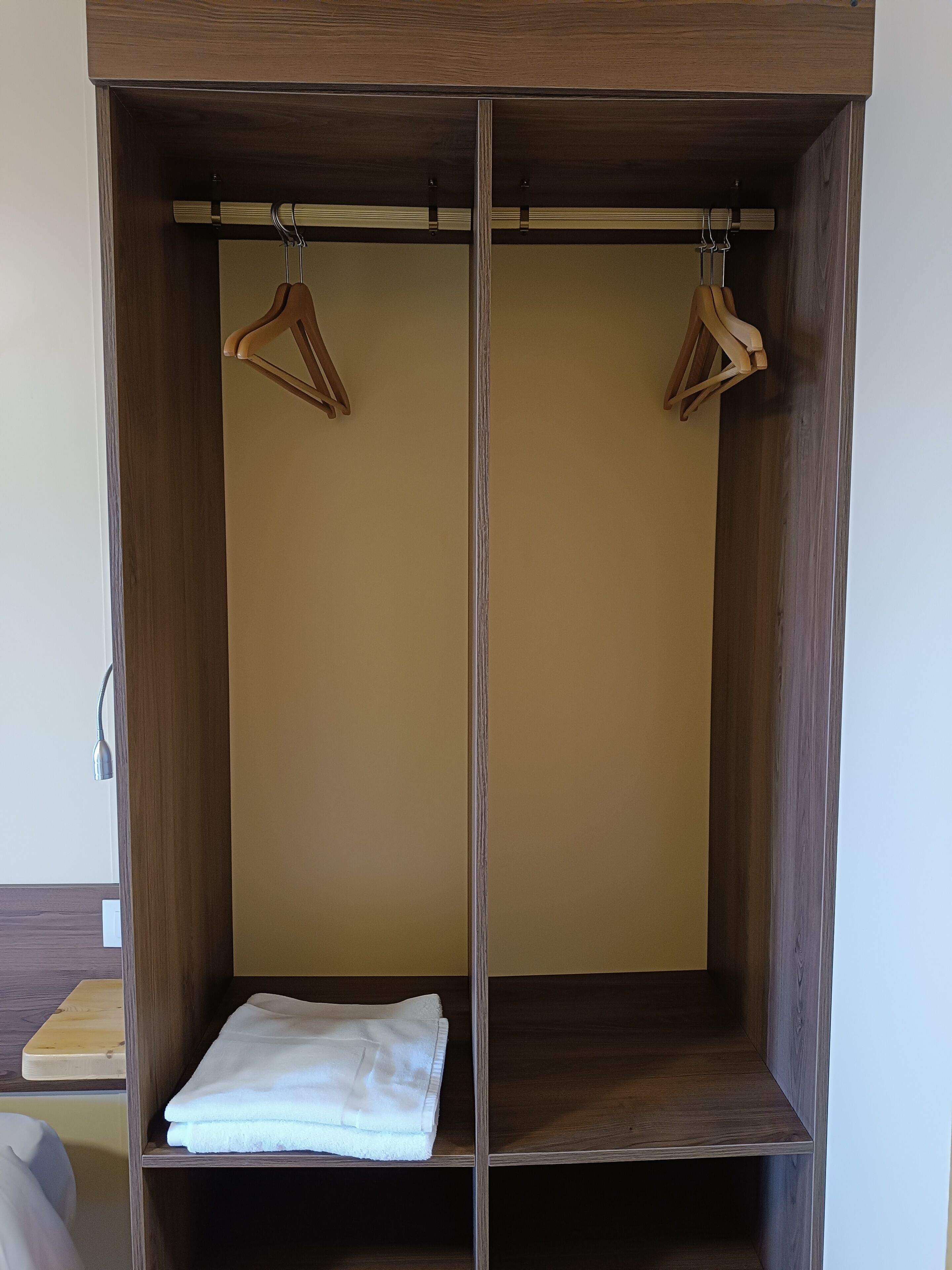 A wardrobe with two wooden hangers and a folded white towel.