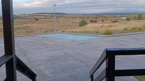 A wooden deck with a view of a landscape, including a road and distant hills.