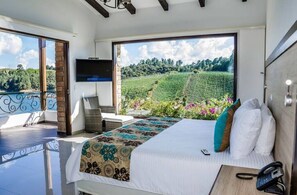 Enjoy a vineyard view from the large bed, with a flat-screen TV and convenient table nearby.
