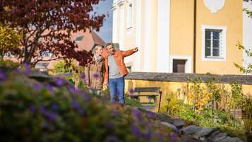 A couple standing in a garden with a yellow building in the background.