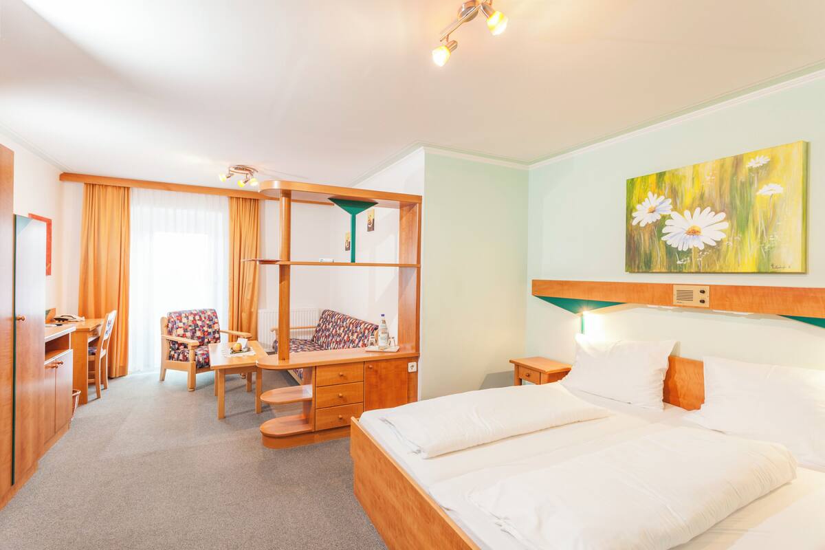 Una habitación de hotel con una cama, un escritorio, una silla, un armario y un cuadro en la pared.