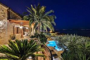 A stone building with a pool, palm trees, and a view of the sea at night. - Villa Tomislav Split - Secluded Mediterranean hacienda (Split)