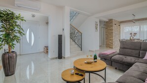 Un'ampia zona giorno con una scala, un'area pranzo con parete in pietra decorativa e una grande pianta in vaso.