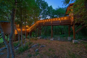 A wooden treehouse with a wooden deck and string lights, surrounded by trees and rocks. - Villa Laura with pool and jacuzzi (Kvarner - Brusići) (Brusići)