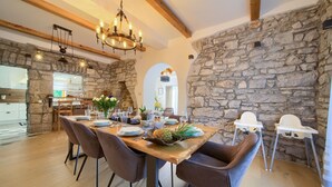 A dining area with a stone wall, wooden beams, and a chandelier. - Villa Laura with pool and jacuzzi (Kvarner - Brusići) (Brusići)