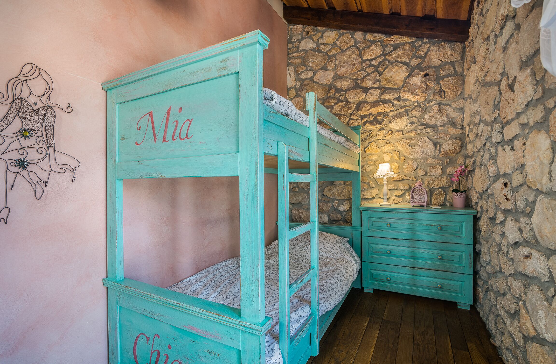 A rustic room with a bunk bed labeled 'Mia' and a dresser.