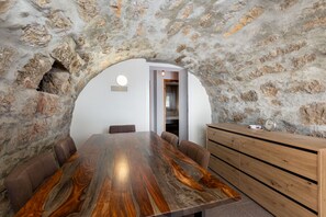 Experience the unique blend of rustic charm and modern style in this cozy room, featuring a curved stone archway and comfortable dining area.