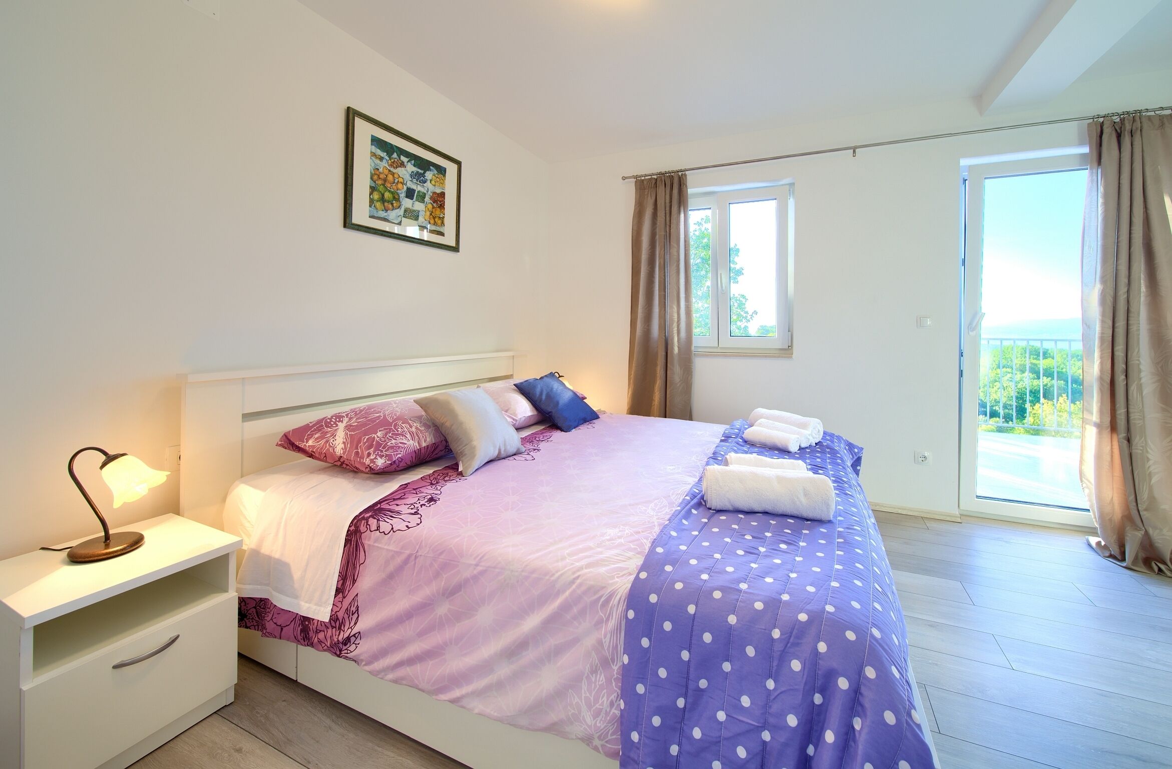 Een slaapkamer met een bed, nachtkastje en een raam met gordijnen.