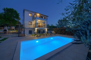 Uma casa de dois andares com piscina, área de estar externa e varanda.