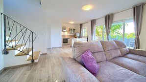 A modern living room with a sofa, a staircase, and a kitchen in the background. - Villa Elena (Kvarner - Poljica) (Poljica)