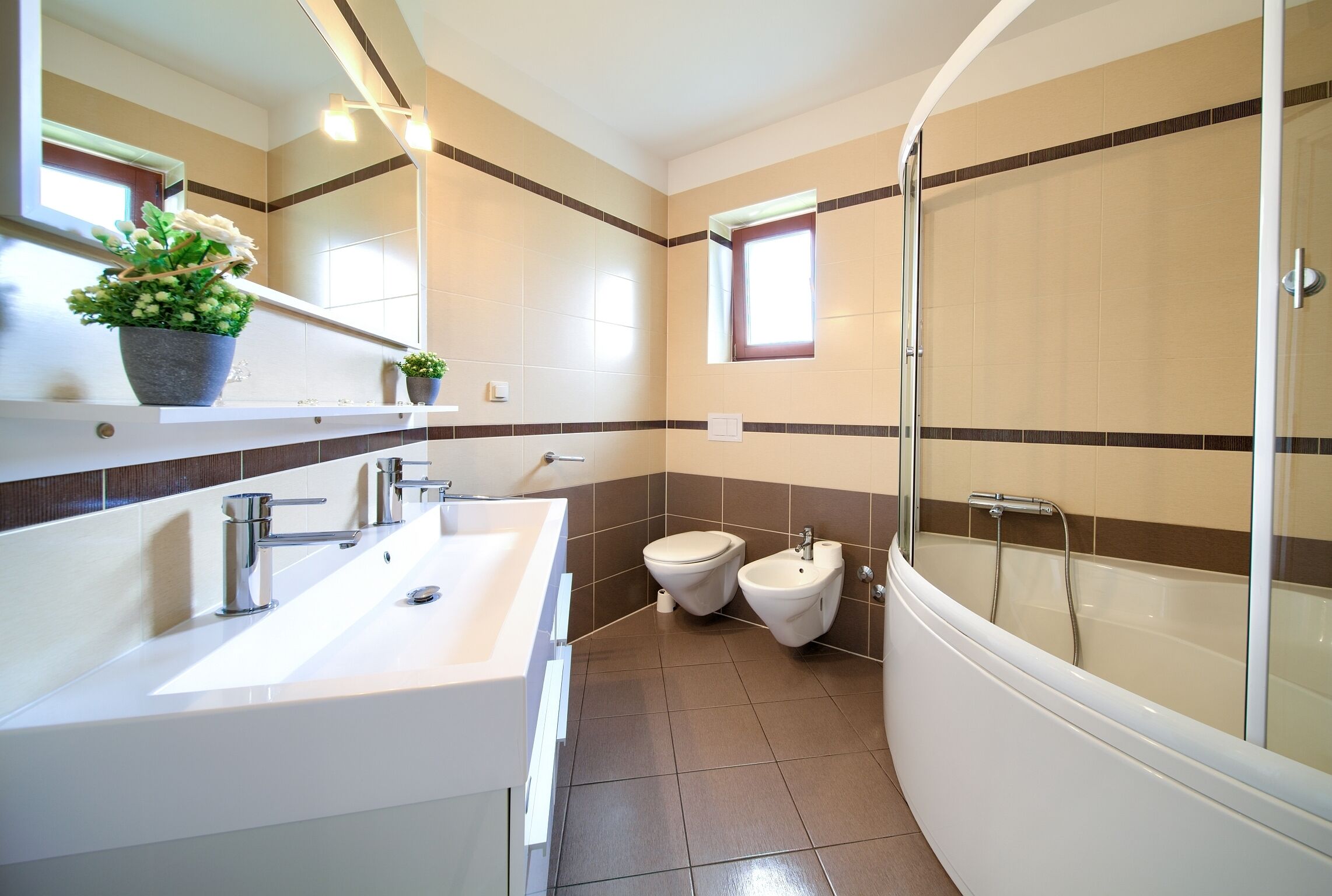 A modern bathroom with a large sink, two toilets, and a glass-enclosed shower.
