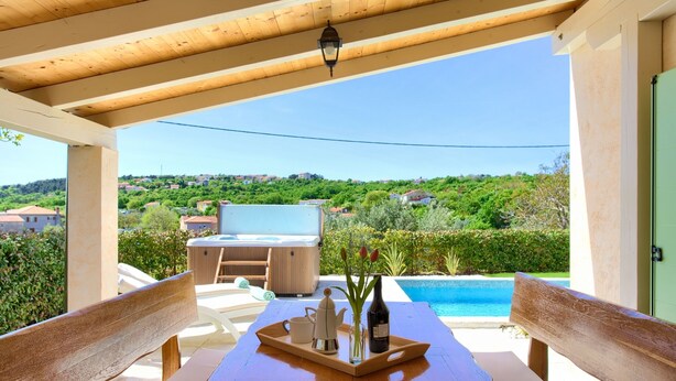 A wooden table with a tray holding a teapot, cup, and bottle, set on a balcony overlooking a swimming pool and a scenic landscape. - Villa Luca with pool and jacuzzi (Kvarner - Vrh) (Vrh)