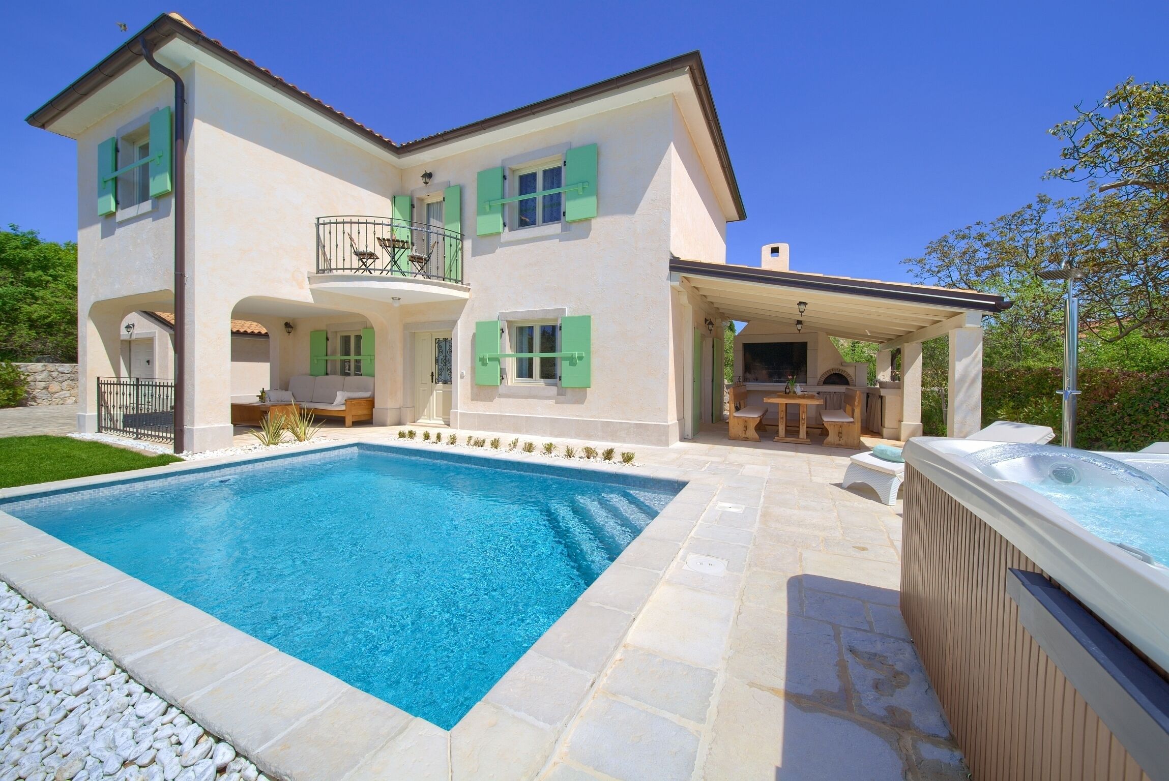 A two-story house with a swimming pool, outdoor seating, and a hot tub.
