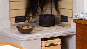 A stone fireplace with a wooden mantel, a bowl of food on the hearth, and a pot on the mantel. - Villa Luca with pool and jacuzzi (Kvarner - Vrh) (Vrh)
