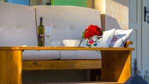 A wooden bench with a cushion, a wine bottle, a glass, and a vase with red flowers. - Villa Luca with pool and jacuzzi (Kvarner - Vrh) (Vrh)