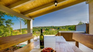 An outdoor dining area with a wooden table, a bottle of wine, and a plate of food. - Villa Luca with pool and jacuzzi (Kvarner - Vrh) (Vrh)