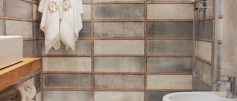 A modern bathroom with a tiled wall, a bathtub, a toilet, and a sink.