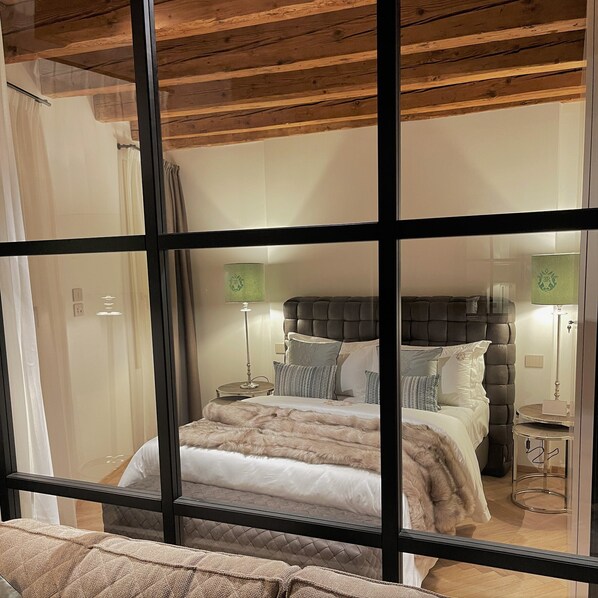 A bedroom with a large bed, a headboard, bedside tables, lamps, and a mirror. - Elegance Room (Bassano del Grappa)
