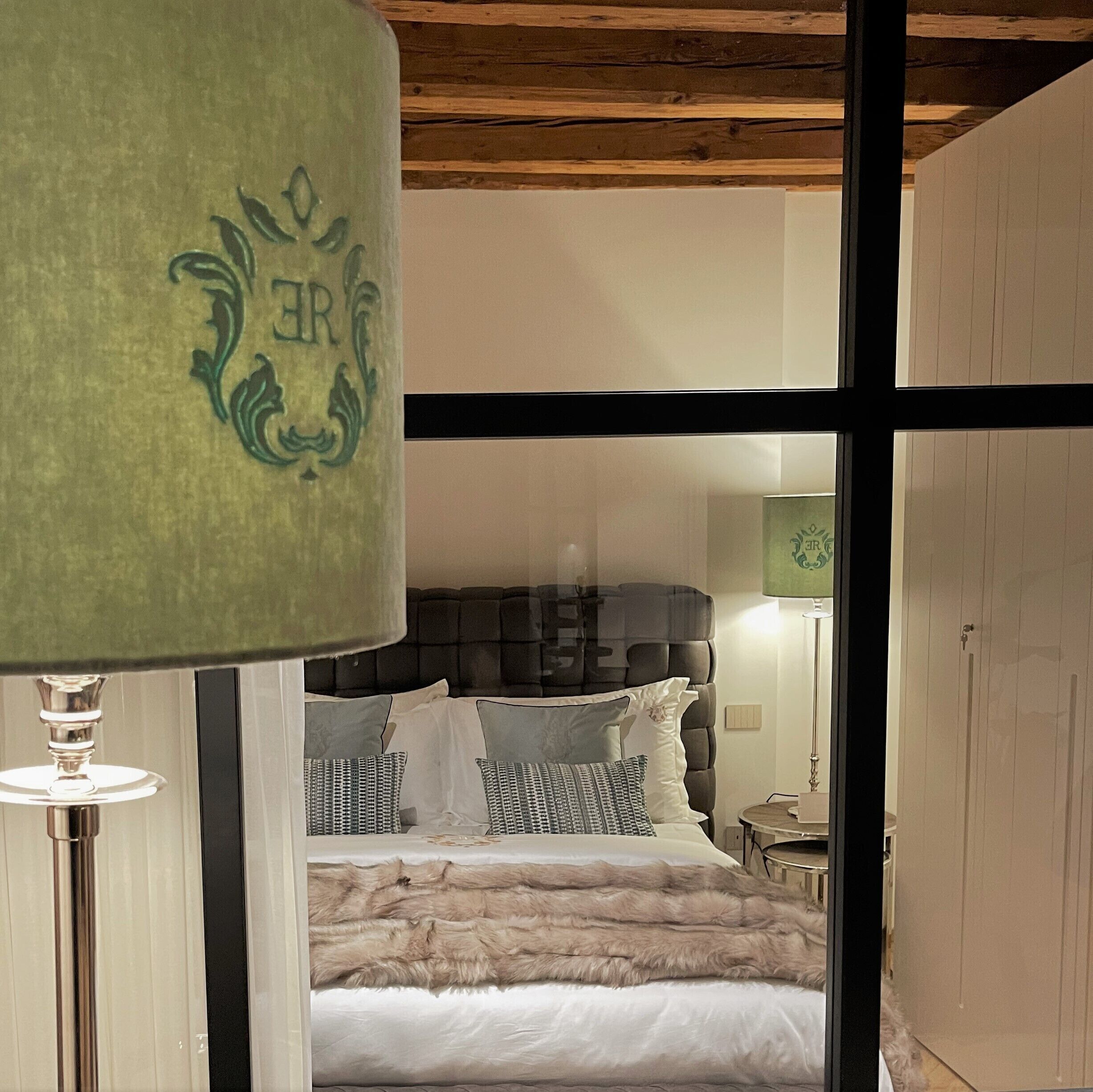 Une chambre à coucher avec un lit, des oreillers, un plaid en fausse fourrure et une lampe.