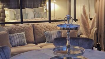 A modern living room with a sofa set, a round table with a tray, and a lamp.