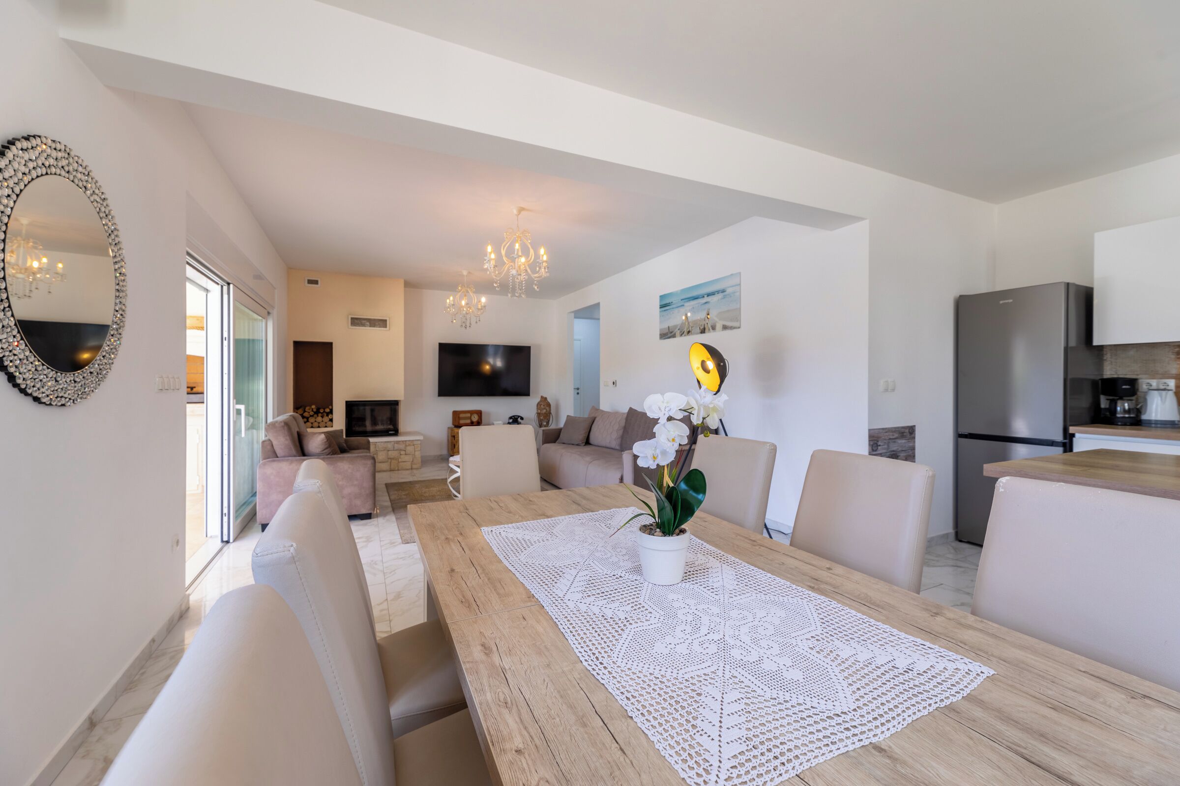 Ein modernes Wohnzimmer mit einem Holzesstisch, weißen Sofas und einem großen Spiegel.