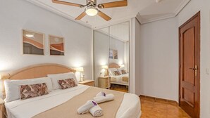 Une chambre d’hôtel avec un lit, un ventilateur de plafond, un miroir et une porte en bois.