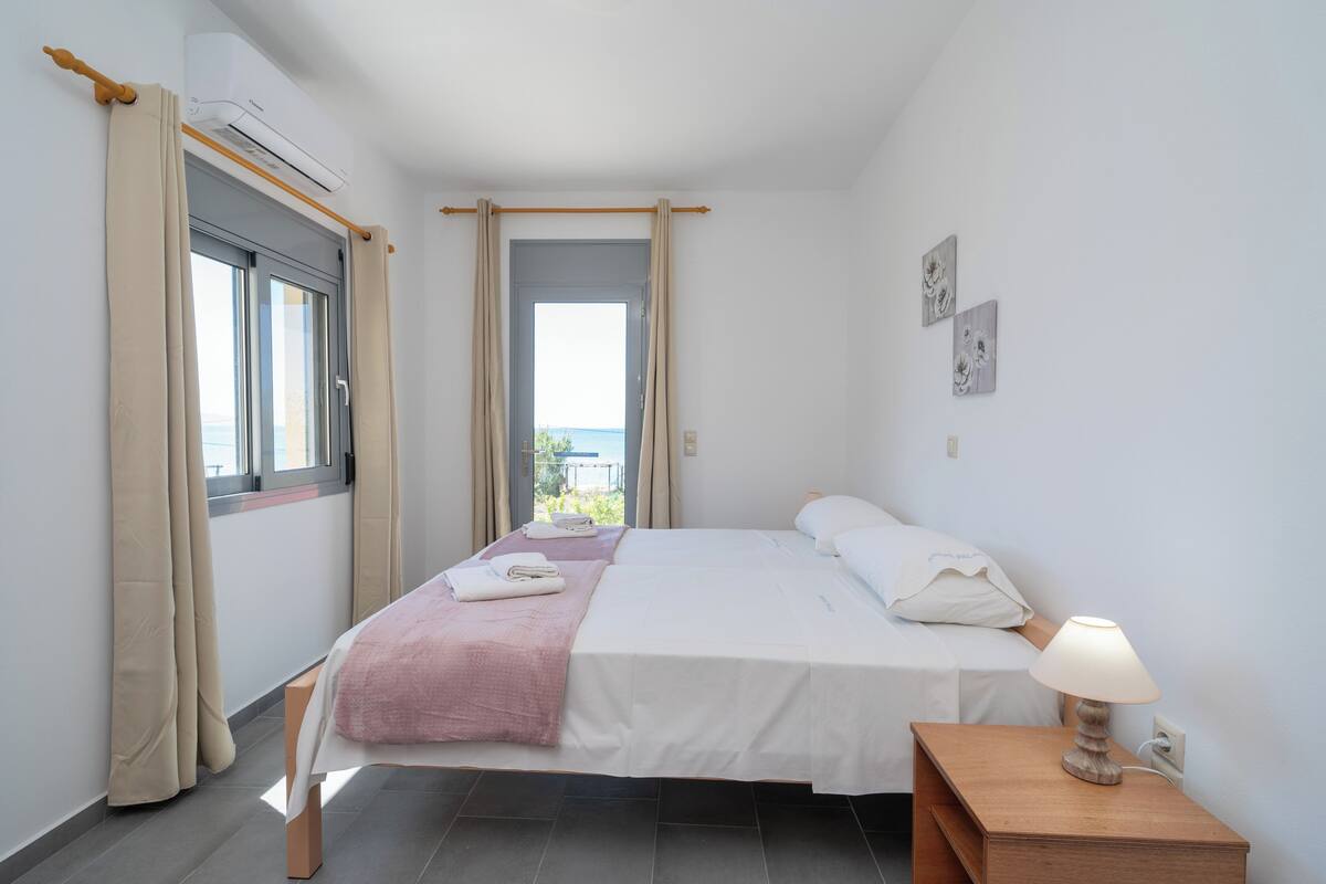 A bedroom with a bed, bedside table, and an air conditioning unit.